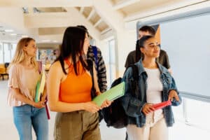 Multiracial group of students walk and talk together through the hallways of the university campus. Education and social inclusion.