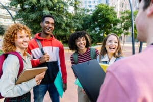 Group of multiracial students relaxing together outdoors standing at campus park. College lifestyle and education concept.